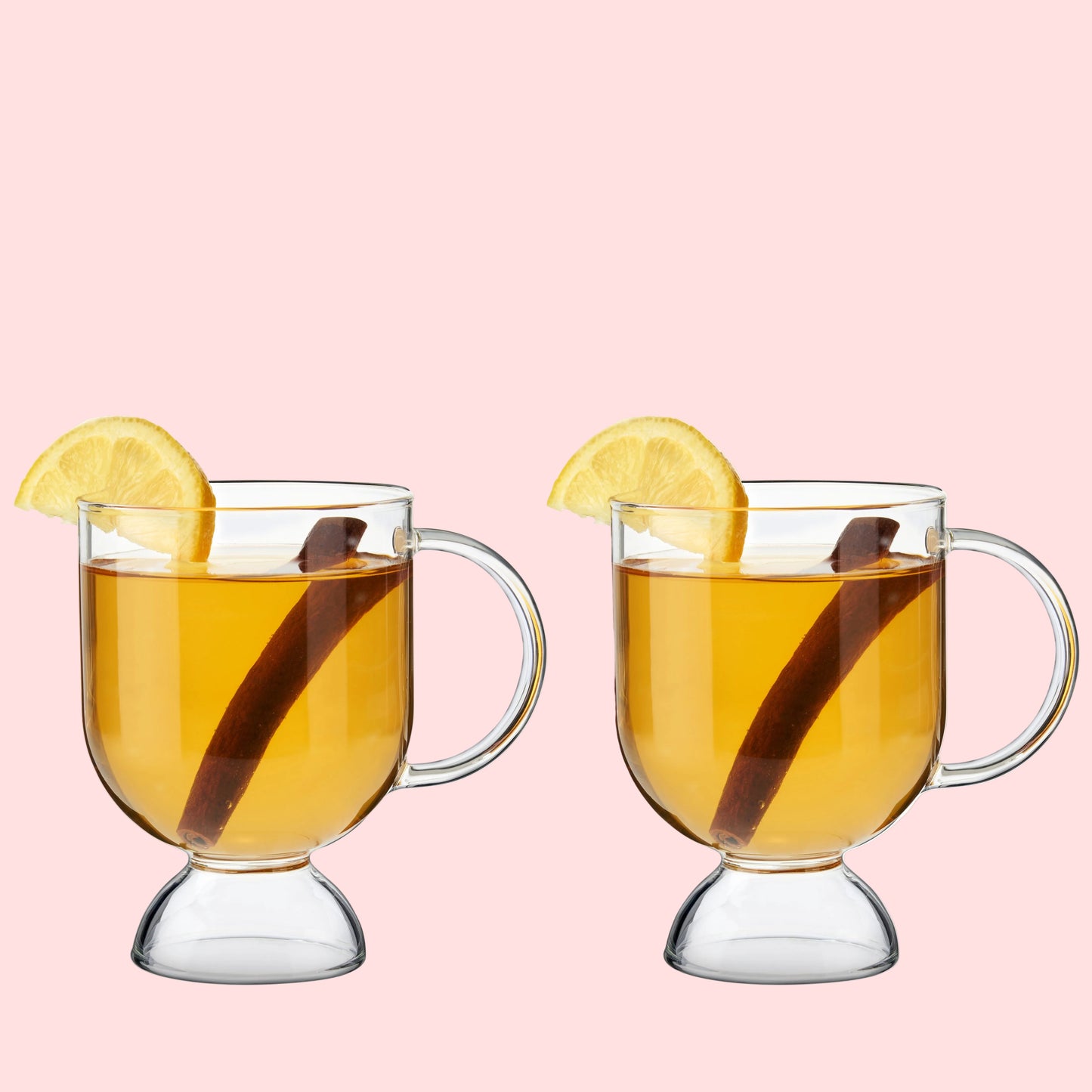 Two glass mugs filled with a warm beverage, garnished with lemon slices and cinnamon sticks, on a white background.