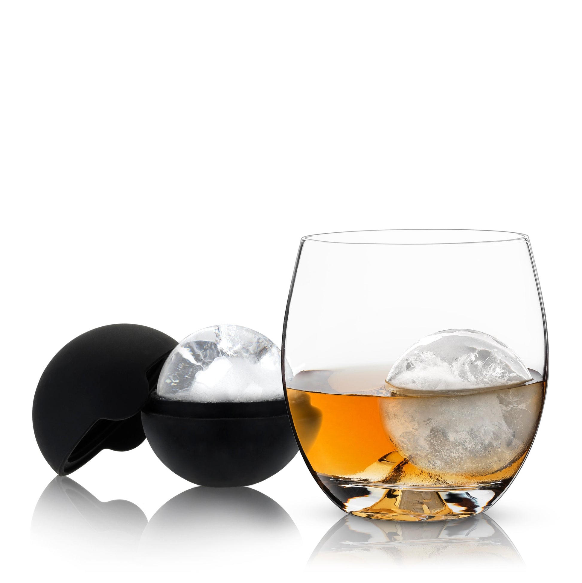 Glass of whiskey with ice cubes and two black silicone ice cube trays on a white background