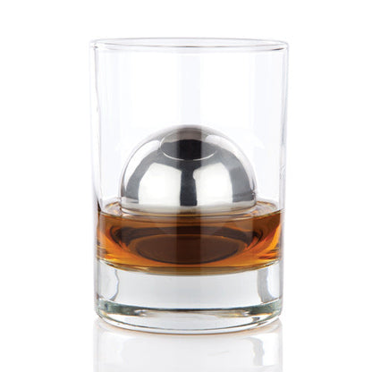 Glass with a metal ball inside, filled with amber liquid on a white background