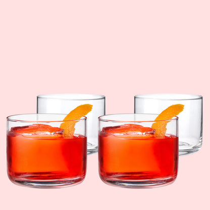 Four glasses of red cocktail with orange slices on a white background