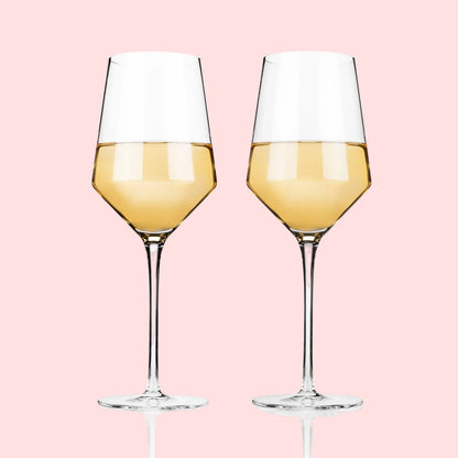 Two wine glasses filled with white wine on a white background