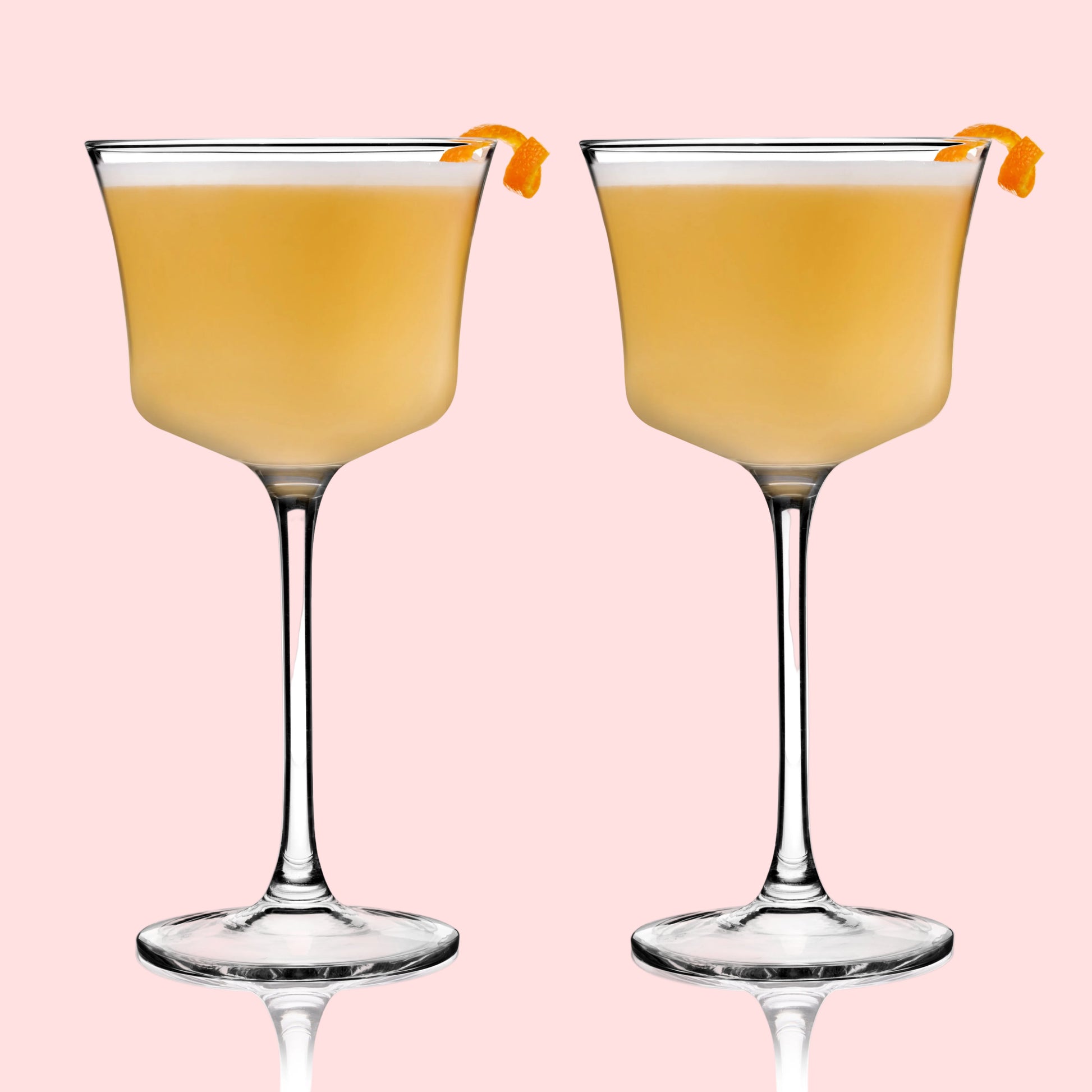 Two glasses of orange cocktail with orange slices on a white background